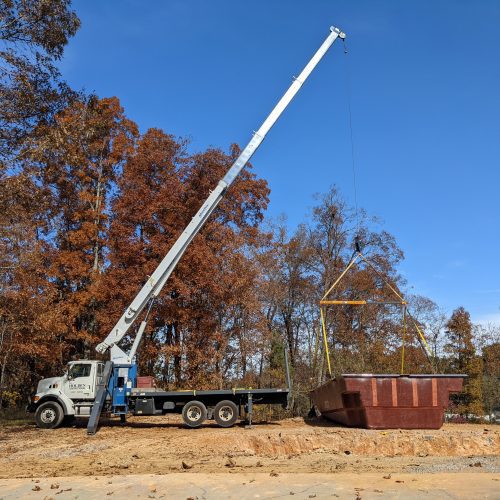 Setting fiberglass swimming pool with boom truck