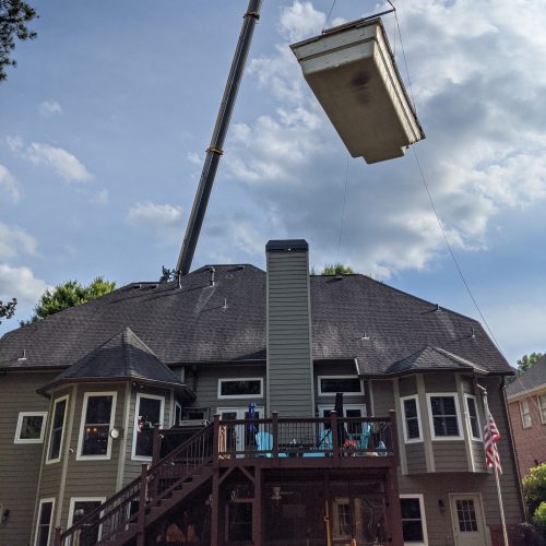 Setting fiberglass swimming pool over house with crane
